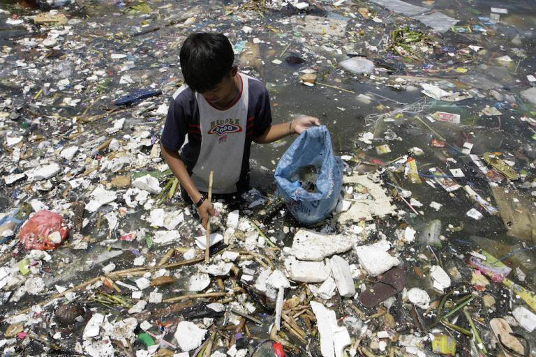 A boy collects plastic near a polluted coastline to sell in Manila.jpg